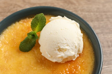 Delicious creme brulee with scoop of ice cream and mint on table, closeup