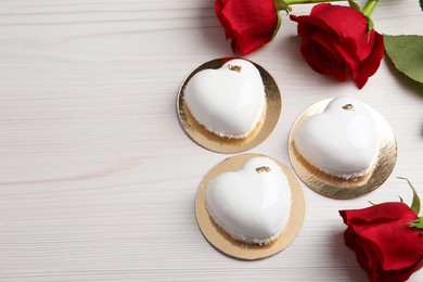 Photo of St. Valentine's Day. Delicious heart shaped cakes and roses on white wooden table, flat lay. Space for text