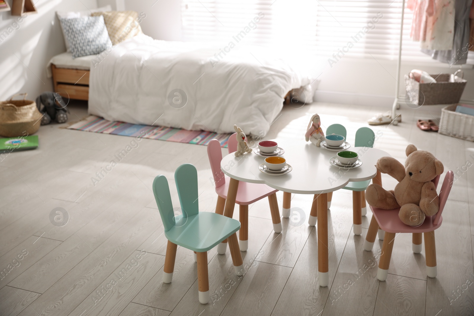 Photo of Small table and chairs with bunny ears in children's room interior