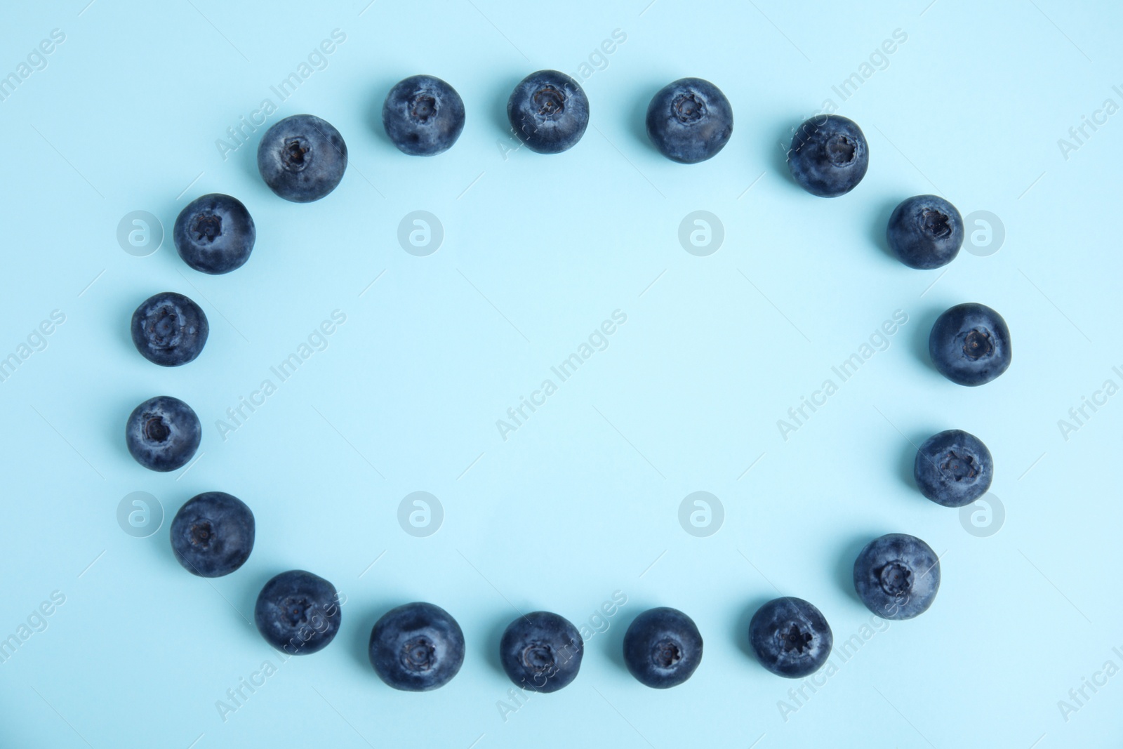 Photo of Frame of fresh ripe blueberries on light blue background, flat lay. Space for text