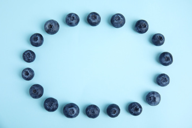 Frame of fresh ripe blueberries on light blue background, flat lay. Space for text