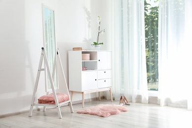 Photo of Stylish living room interior with chest of drawers and mirror