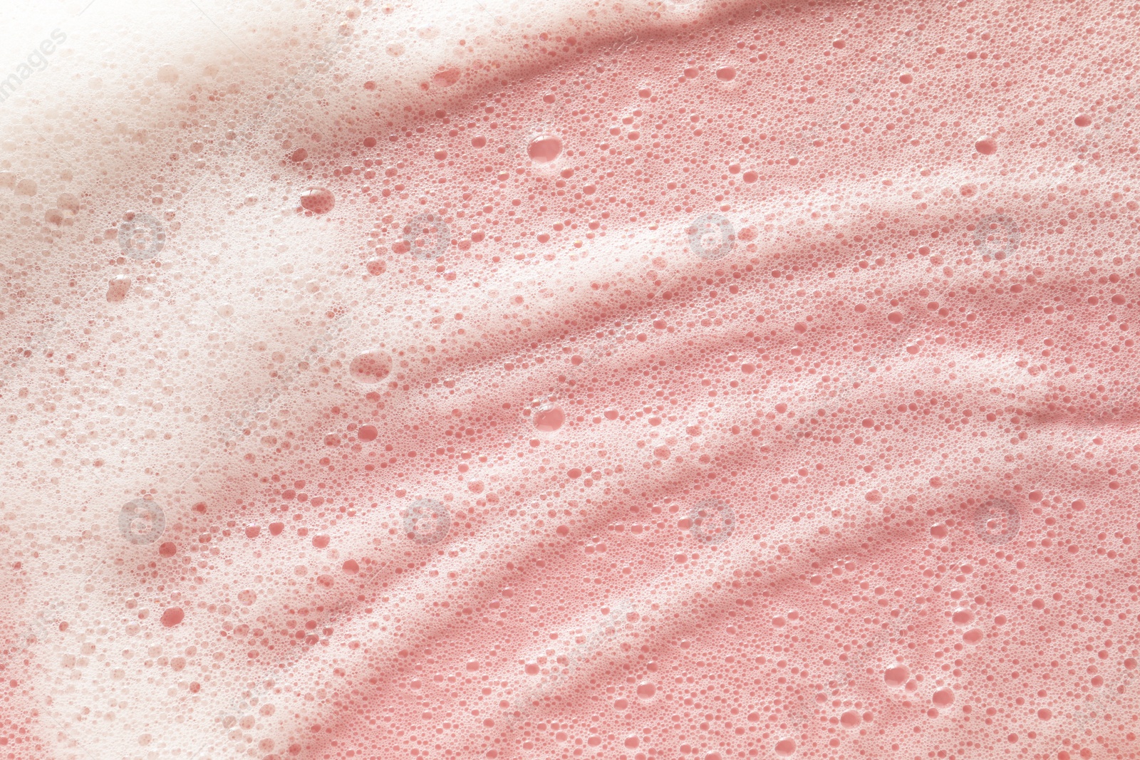 Photo of White washing foam on pale pink background, top view