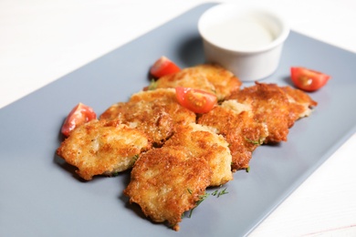 Photo of Plate with tasty potato fritters and sauce, closeup