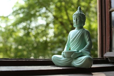 Photo of Decorative Buddha statue on wooden windowsill, space for text