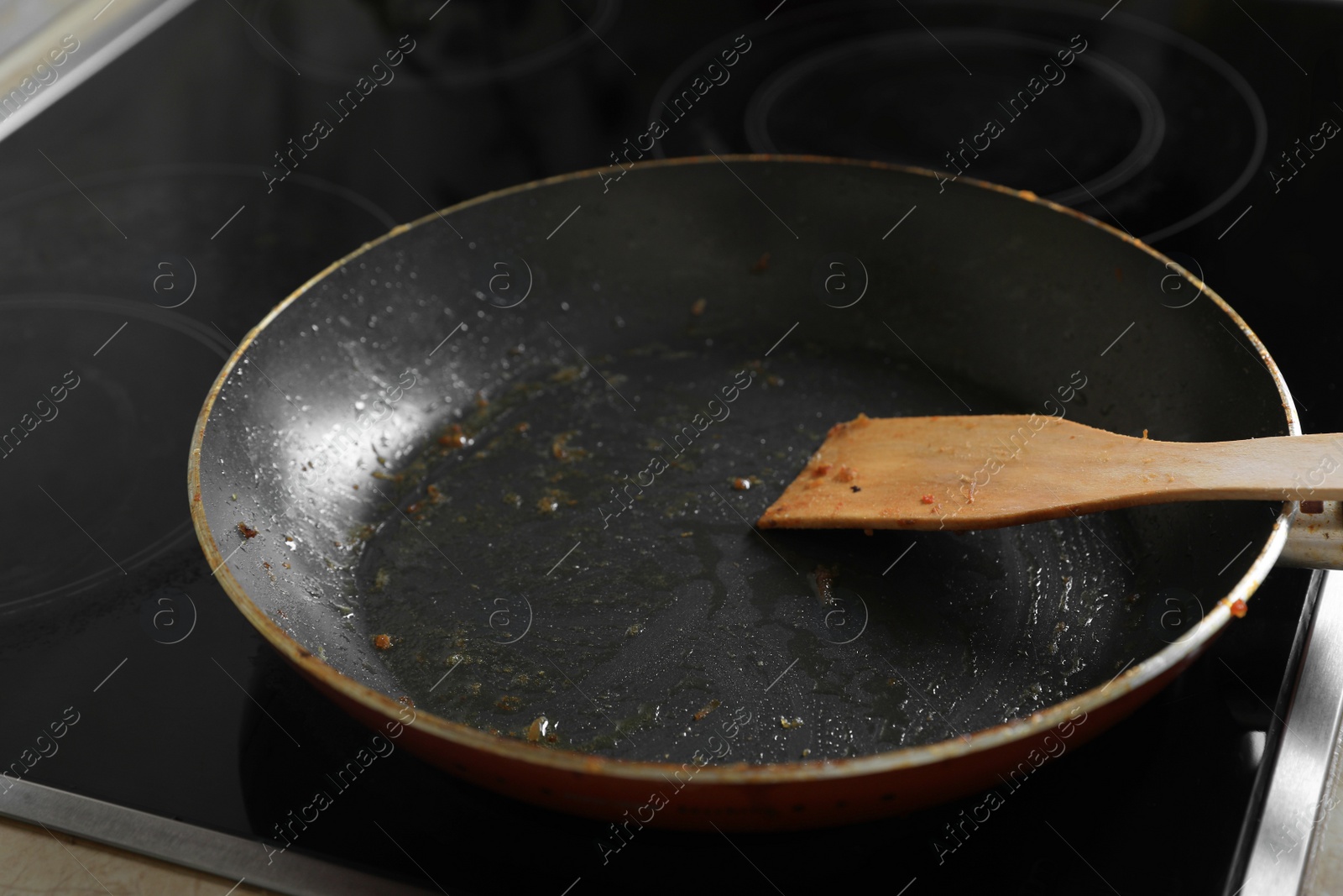 Photo of Frying pan with spatula and used cooking oil on stove