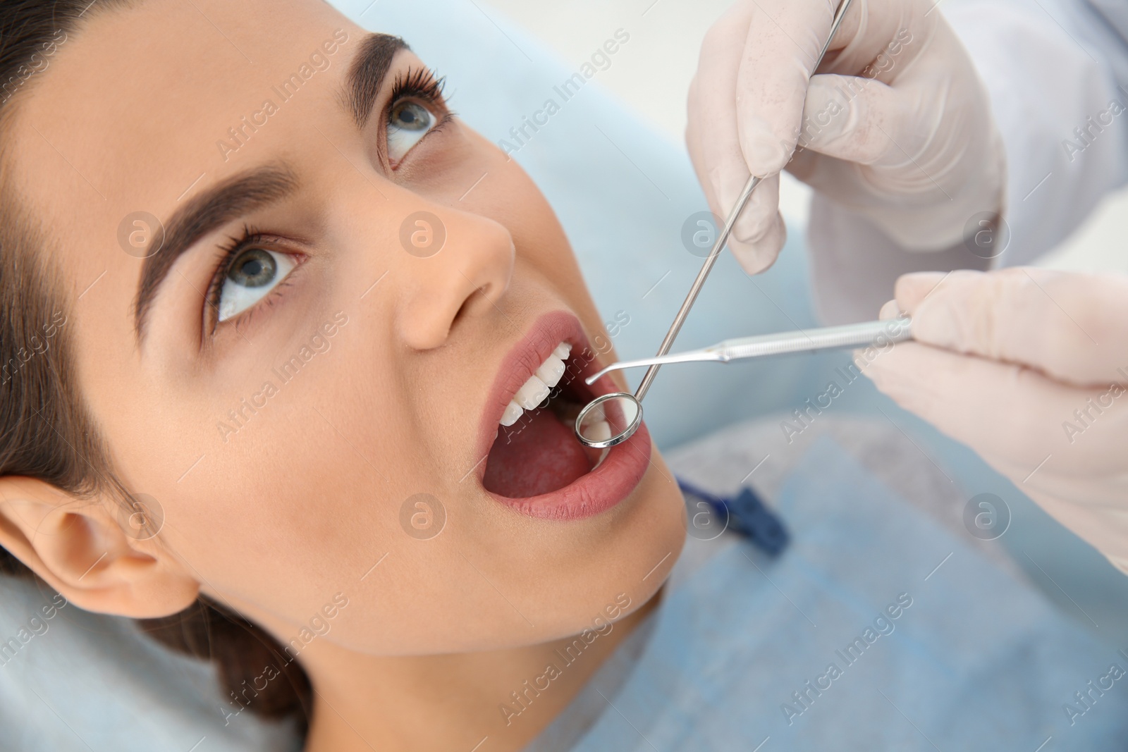 Photo of Dentist examining patient's teeth in modern clinic