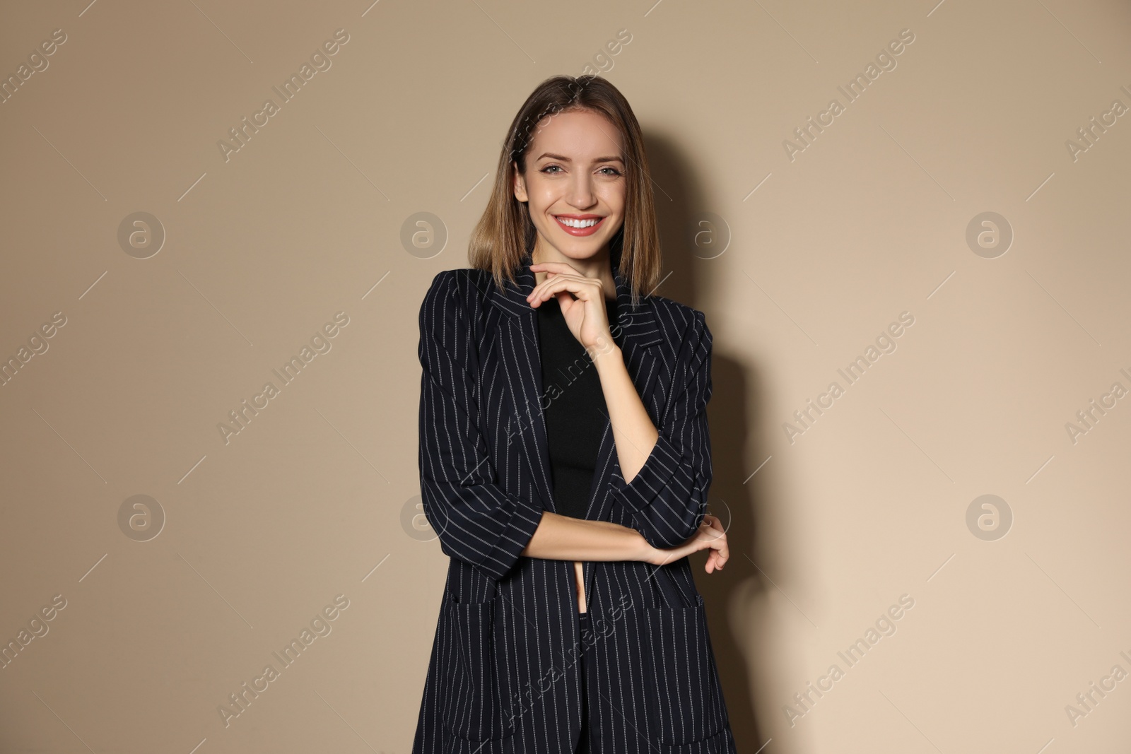 Photo of Portrait of beautiful young woman in fashionable suit on beige background. Business attire