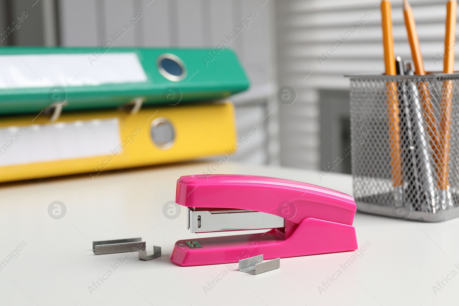 Photo of Stapler and metal staples on white table indoors