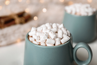 Delicious cocoa drink with marshmallows on table against blurred lights, closeup