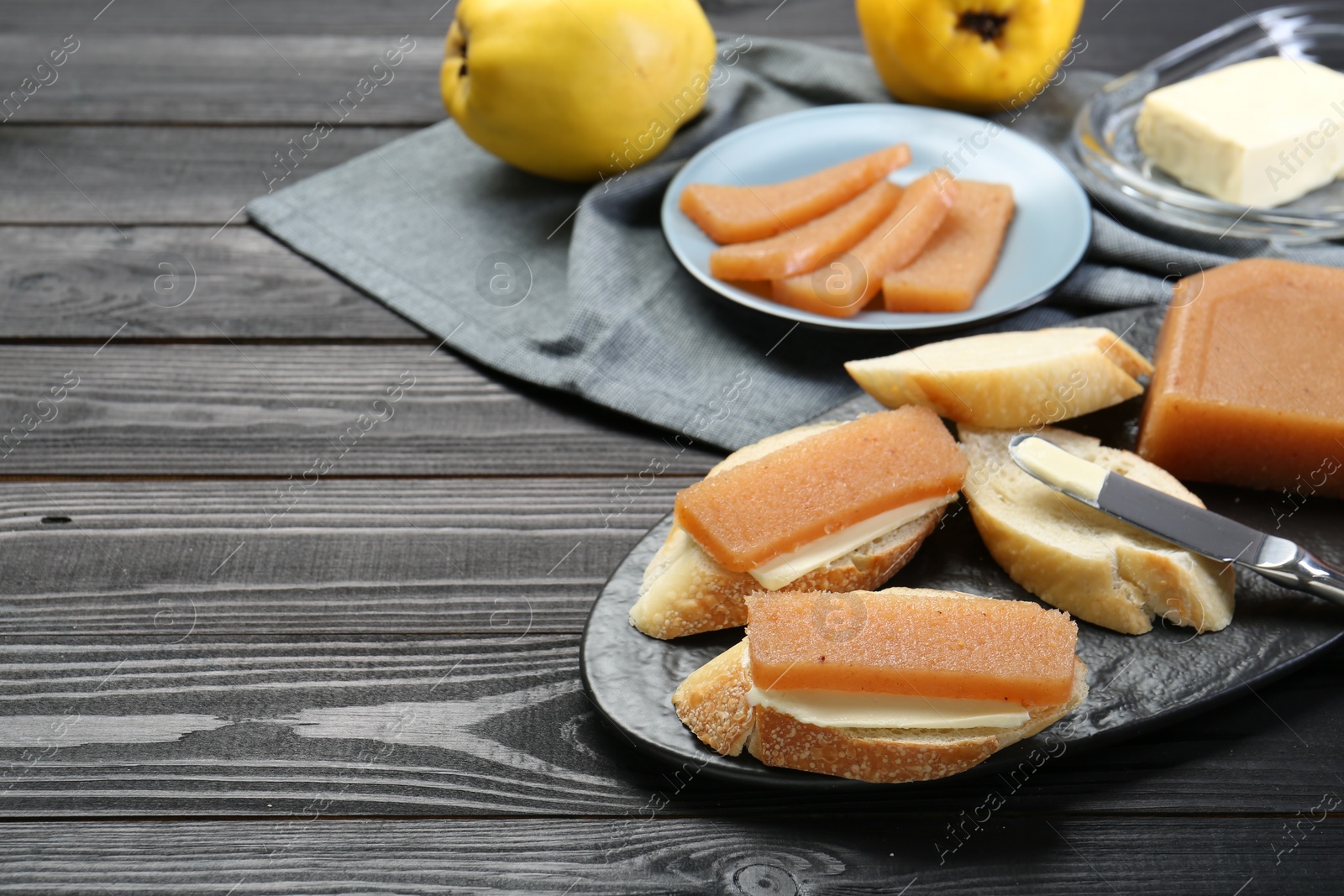 Photo of Tasty sandwiches with quince paste served on black wooden table, space for text