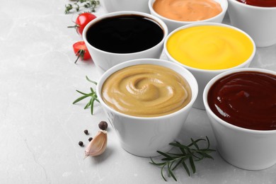Photo of Many bowls with different sauces on light grey table, space for text