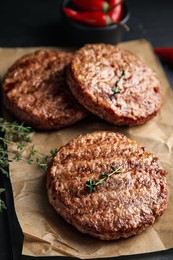 Tasty grilled hamburger patties with thyme on black table, closeup