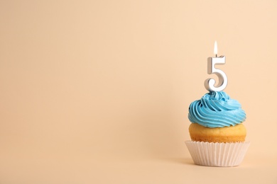 Photo of Birthday cupcake with number five candle on beige background, space for text