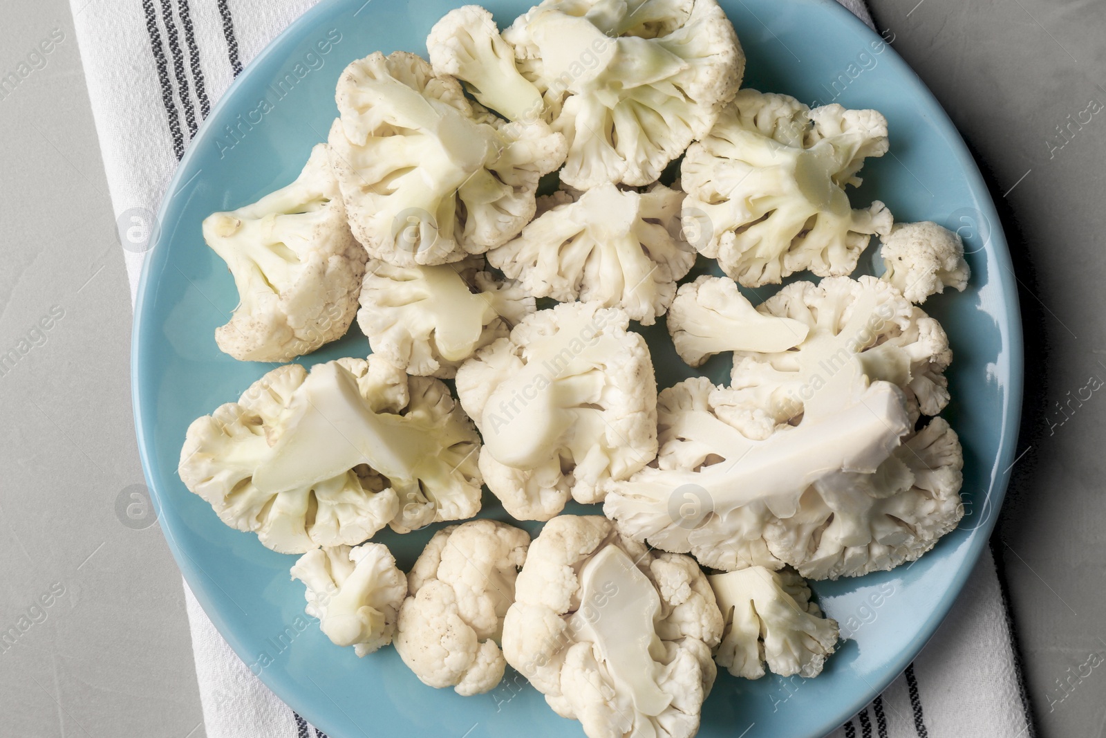 Photo of Plate with cut fresh raw cauliflower on light grey table, top view