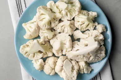 Photo of Plate with cut fresh raw cauliflower on light grey table, top view
