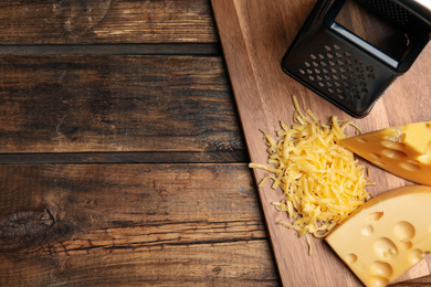 Photo of Tasty grated cheese on wooden table, flat lay. Space for text