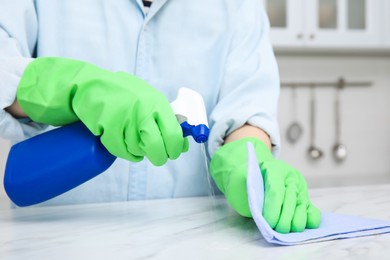 Photo of Woman cleaning white surface with rag and detergent indoors, closeup