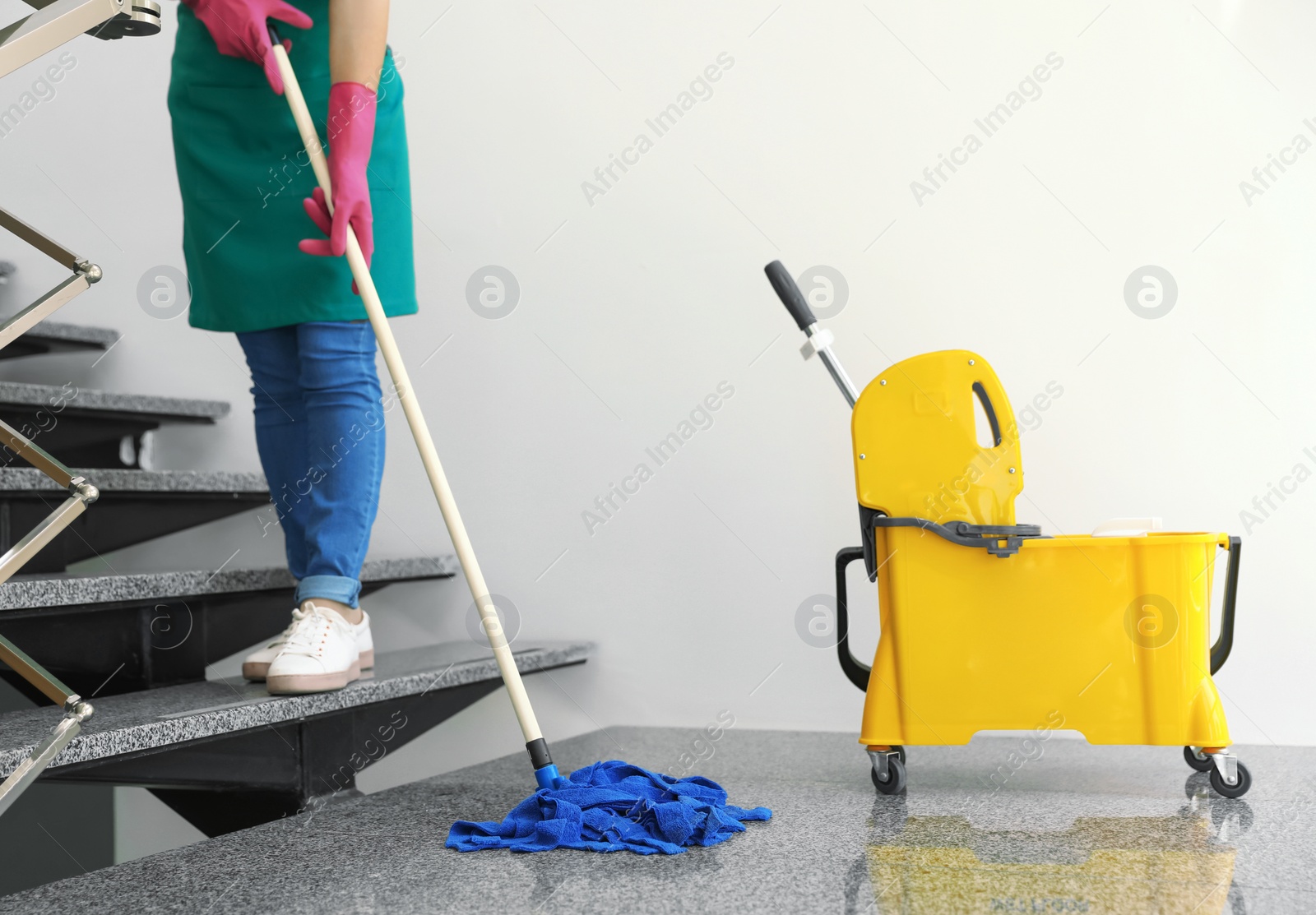 Photo of Young woman with mop cleaning stairs