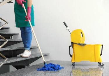 Young woman with mop cleaning stairs