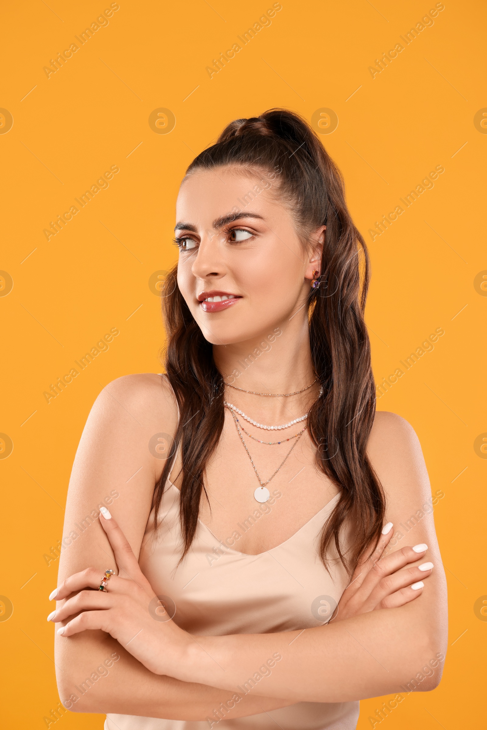 Photo of Beautiful woman with elegant jewelry on orange background