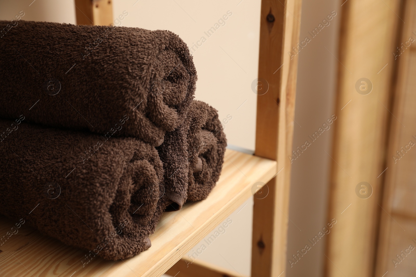 Photo of Soft towels on wooden shelf indoors, closeup. Space for text