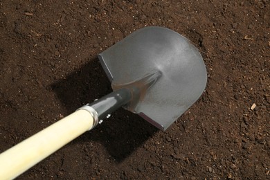 Photo of Metal shovel on fertile soil, top view. Gardening tool