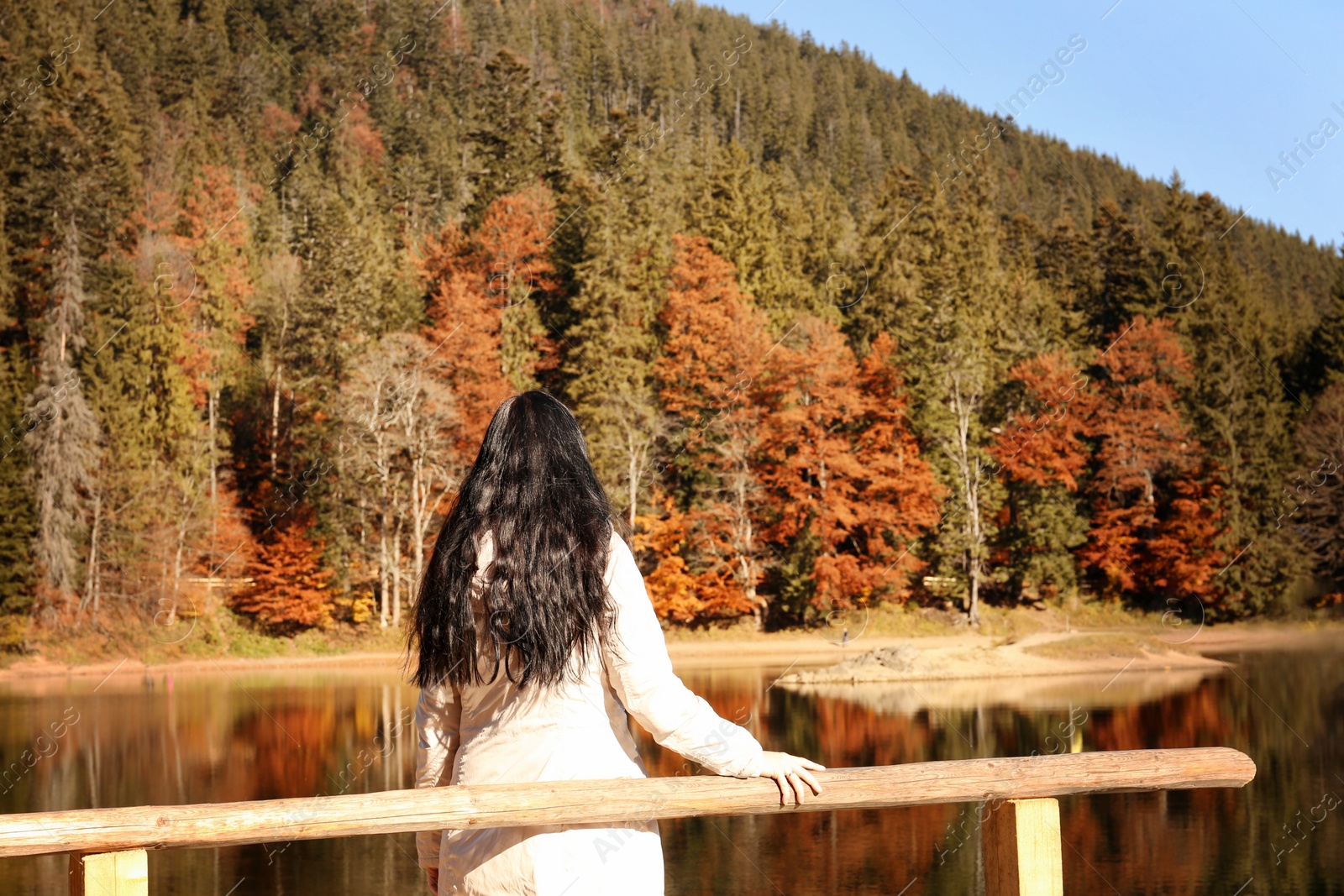 Photo of Woman enjoying view of autumn forest near lake