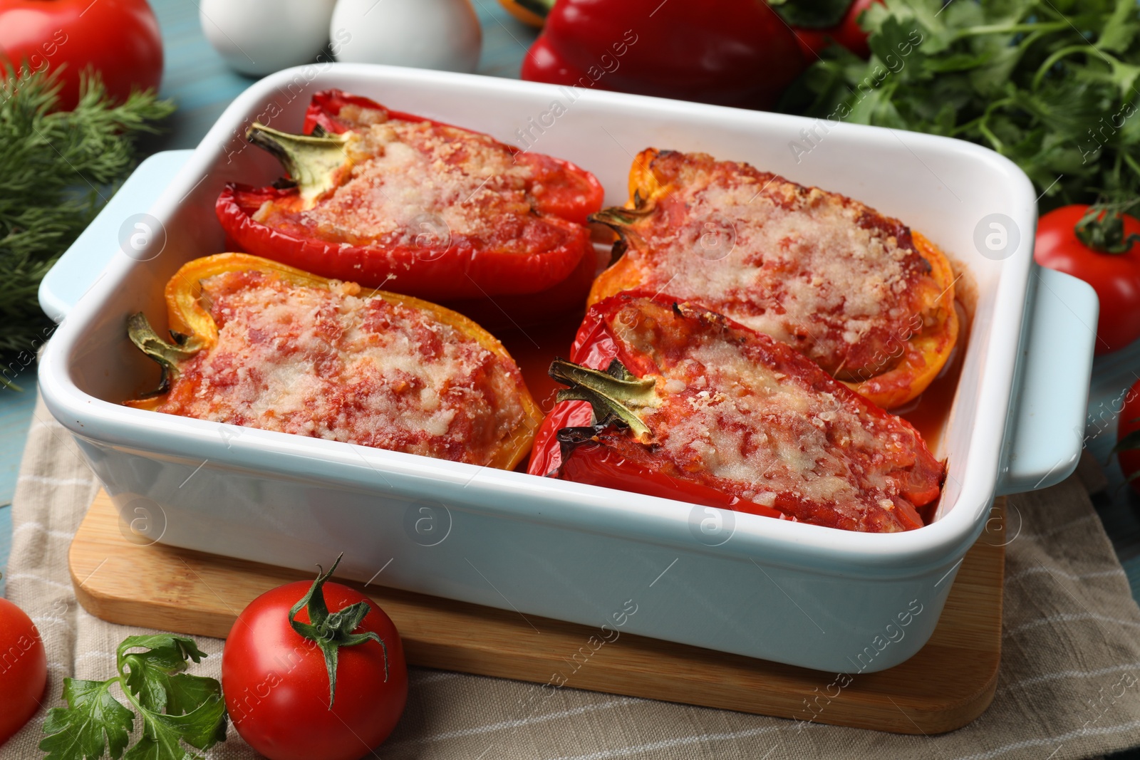 Photo of Tasty stuffed peppers in dish and ingredients on table