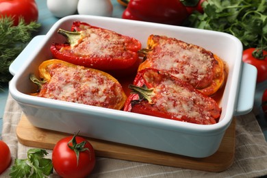 Photo of Tasty stuffed peppers in dish and ingredients on table