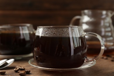 Photo of Hot coffee in glass cups and beans on wooden table, closeup