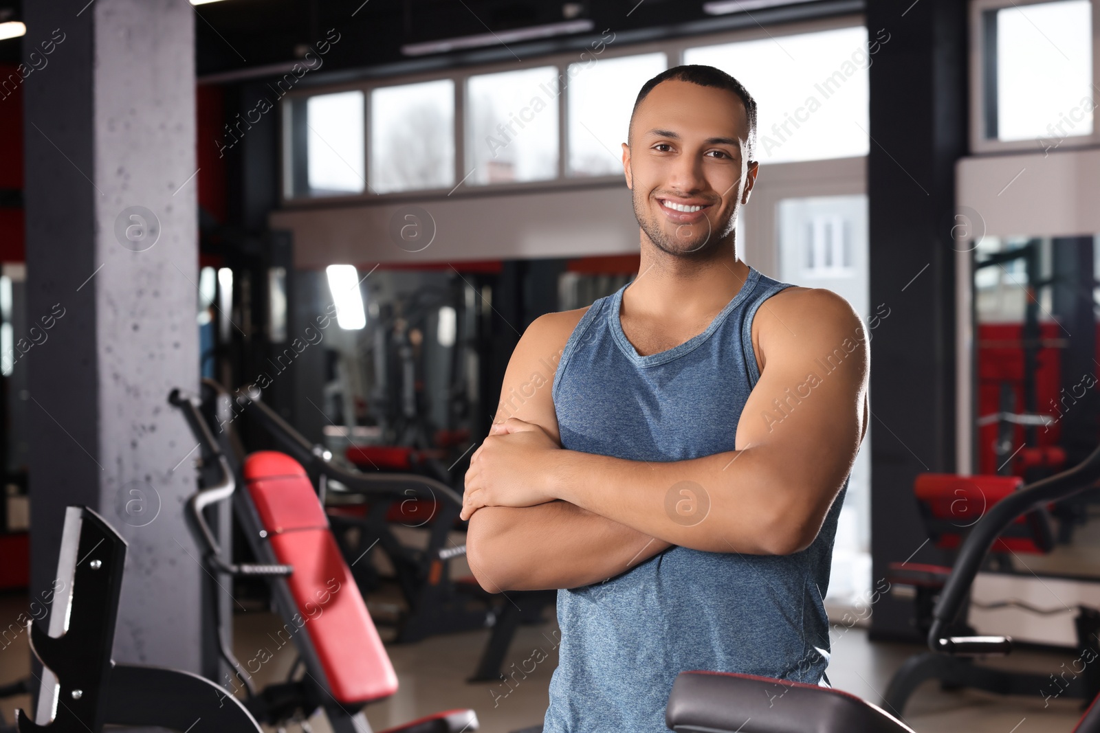 Photo of Happy trainer in modern gym, space for text