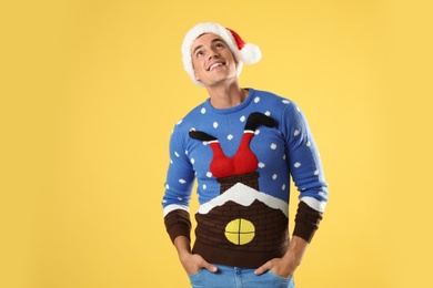 Photo of Man in Christmas sweater and Santa hat on yellow background