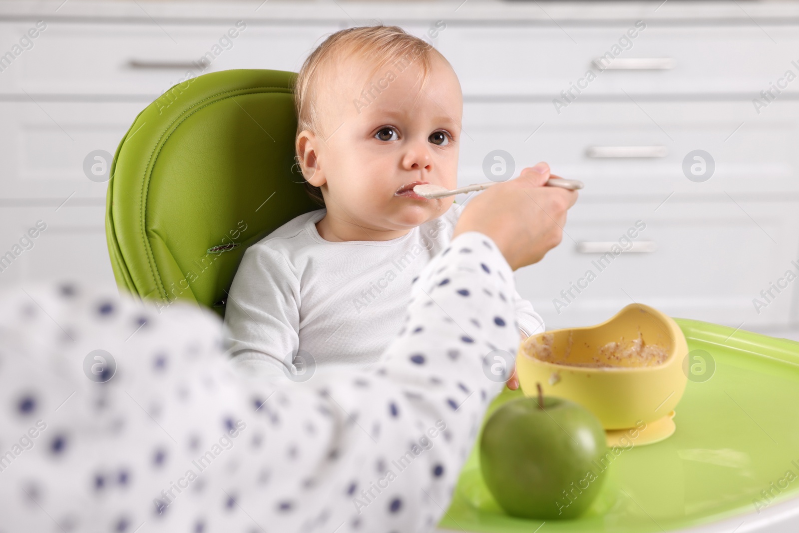 Photo of Mother feeding her cute little baby with healthy food at home