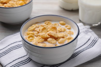 Photo of Tasty cornflakes with milk served in bowl on table