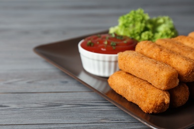 Photo of Plate of cheese sticks with sauce on table, closeup. Space for text