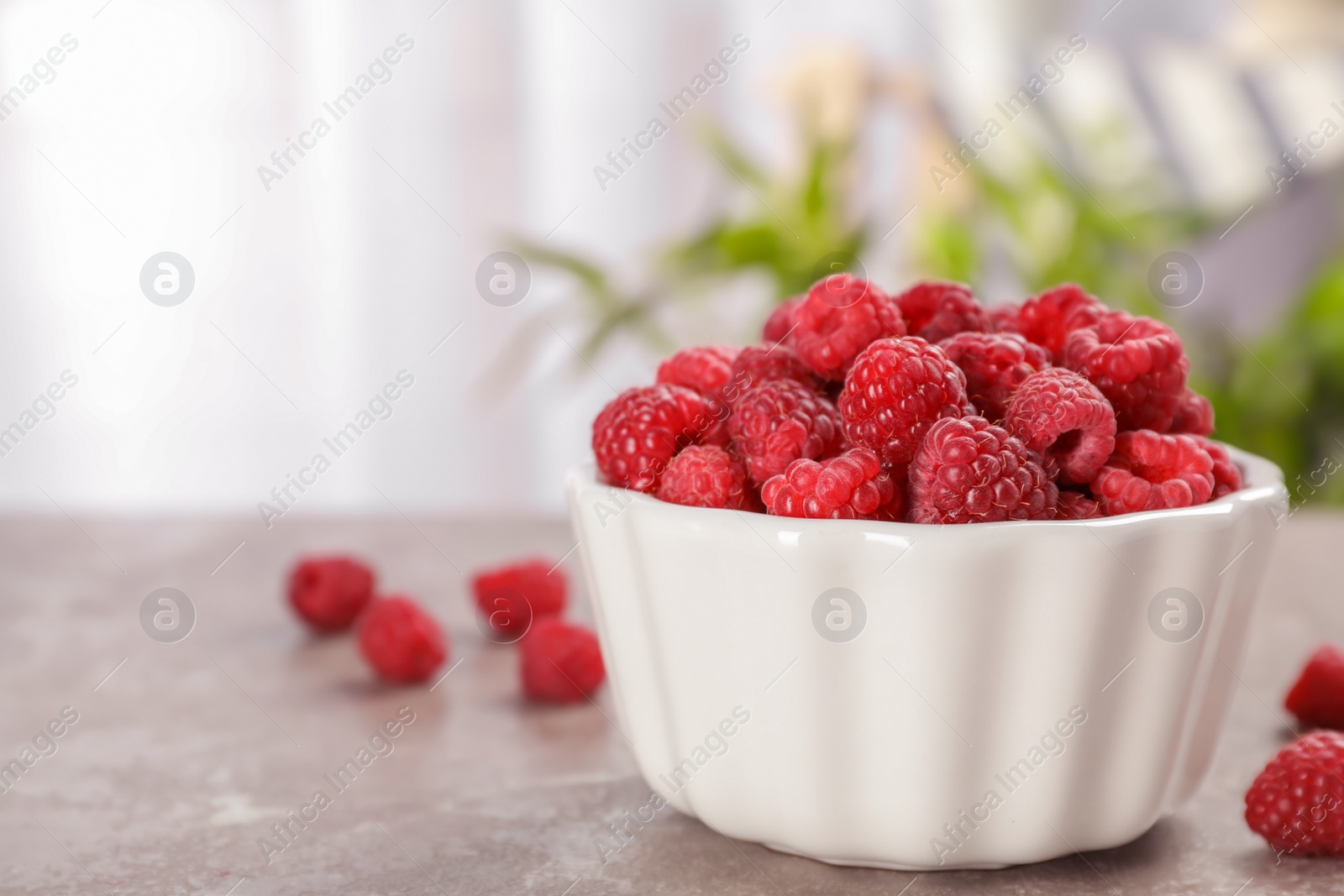 Photo of Bowl with ripe aromatic raspberries on table