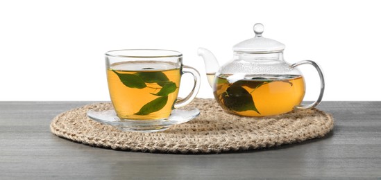 Refreshing green tea in cup and teapot on grey wooden table against white background