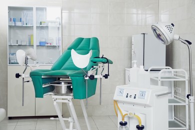 Photo of Examination room with gynecological chair and medical equipment in clinic