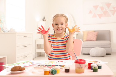Photo of Cute little child painting with palms at table