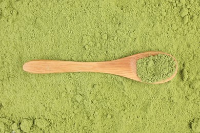 Photo of Wooden spoon on green matcha powder, top view
