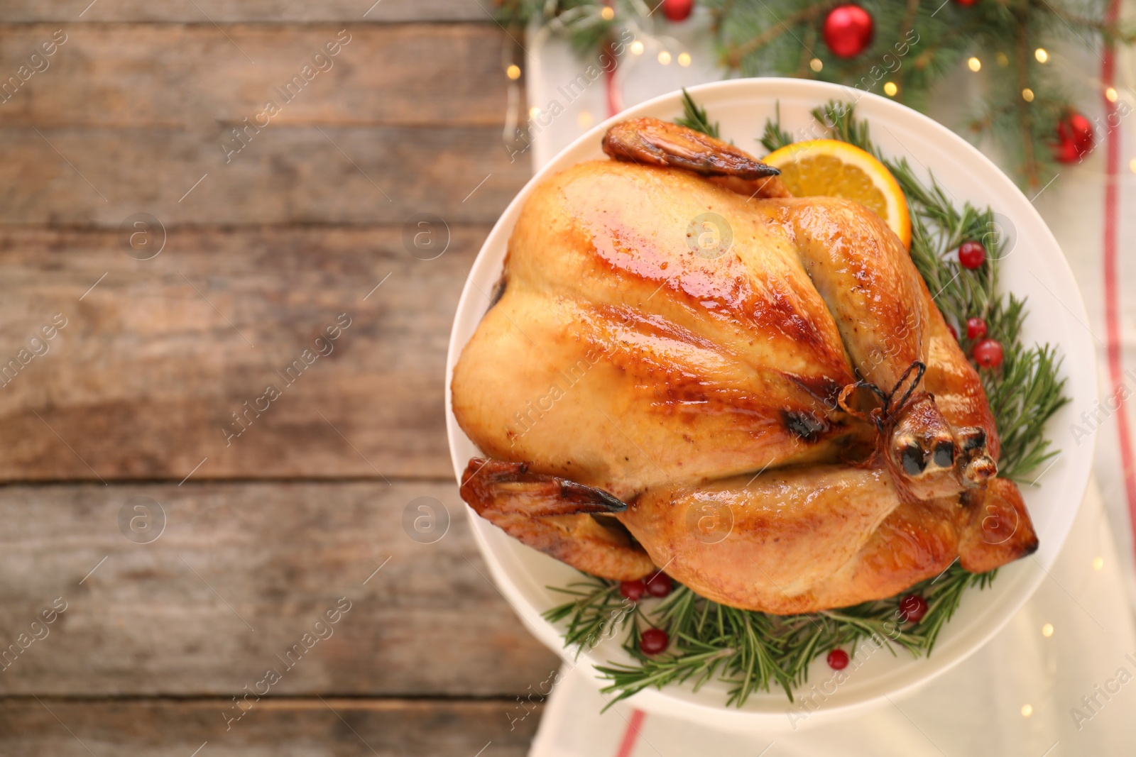 Photo of Platter of cooked turkey with garnish and Christmas decoration on wooden background, top view. Space for text