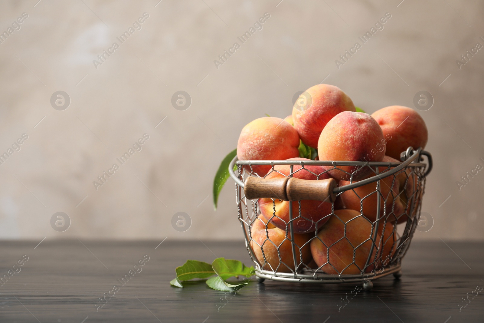 Photo of Basket with ripe peaches on wooden table