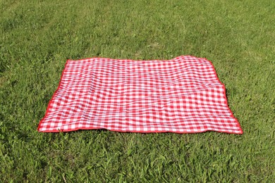 Photo of Checkered picnic tablecloth on fresh green grass outdoors