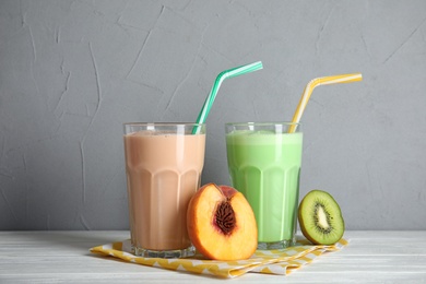 Glasses of tasty milk shakes  and fresh fruits on table