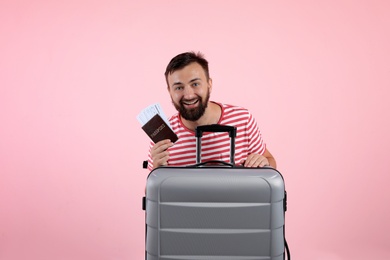 Man with suitcase and passport on color background. Vacation travel