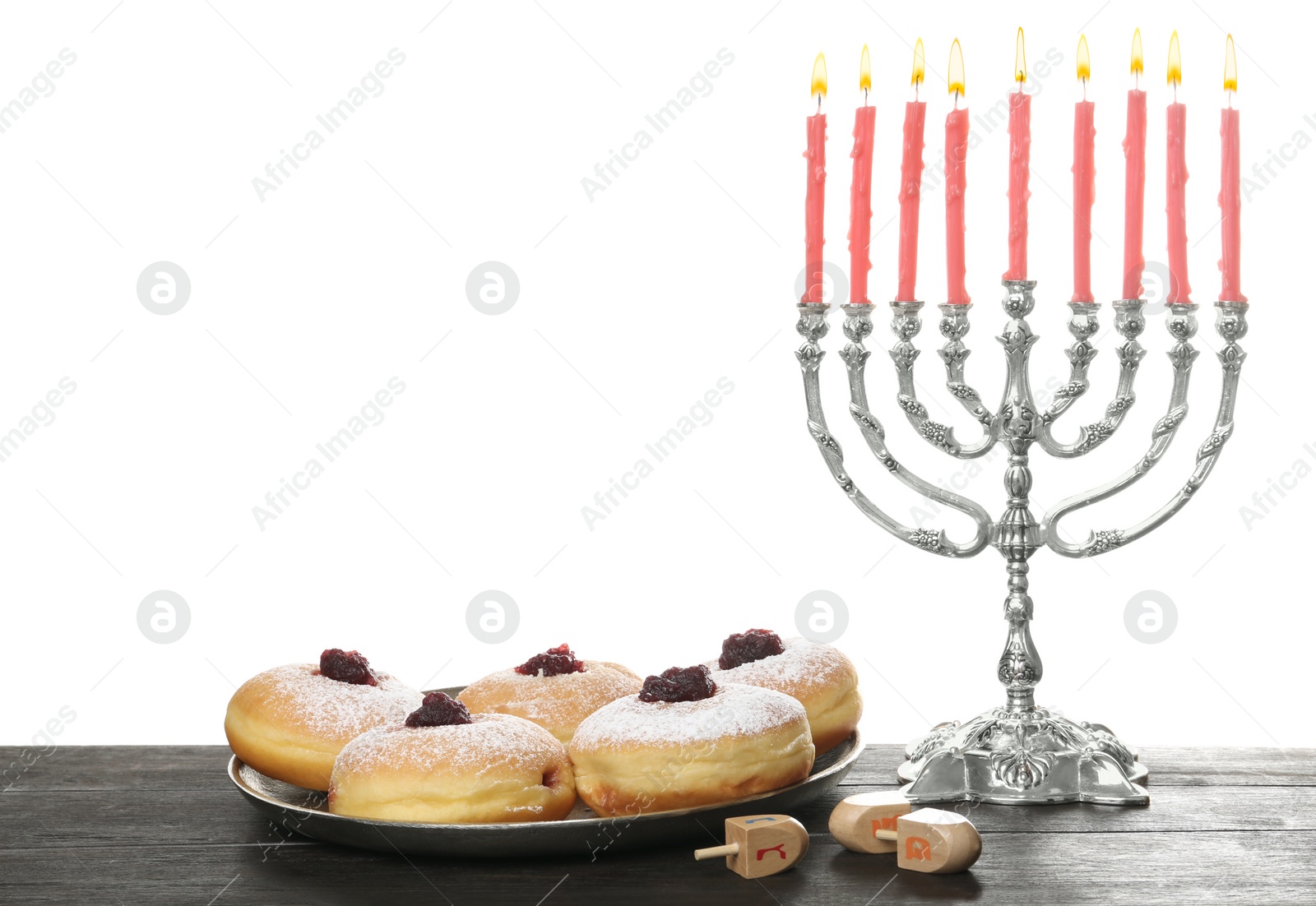 Photo of Silver menorah near sufganiyot and dreidels with symbols He, Pe, Nun, Gimel on white background