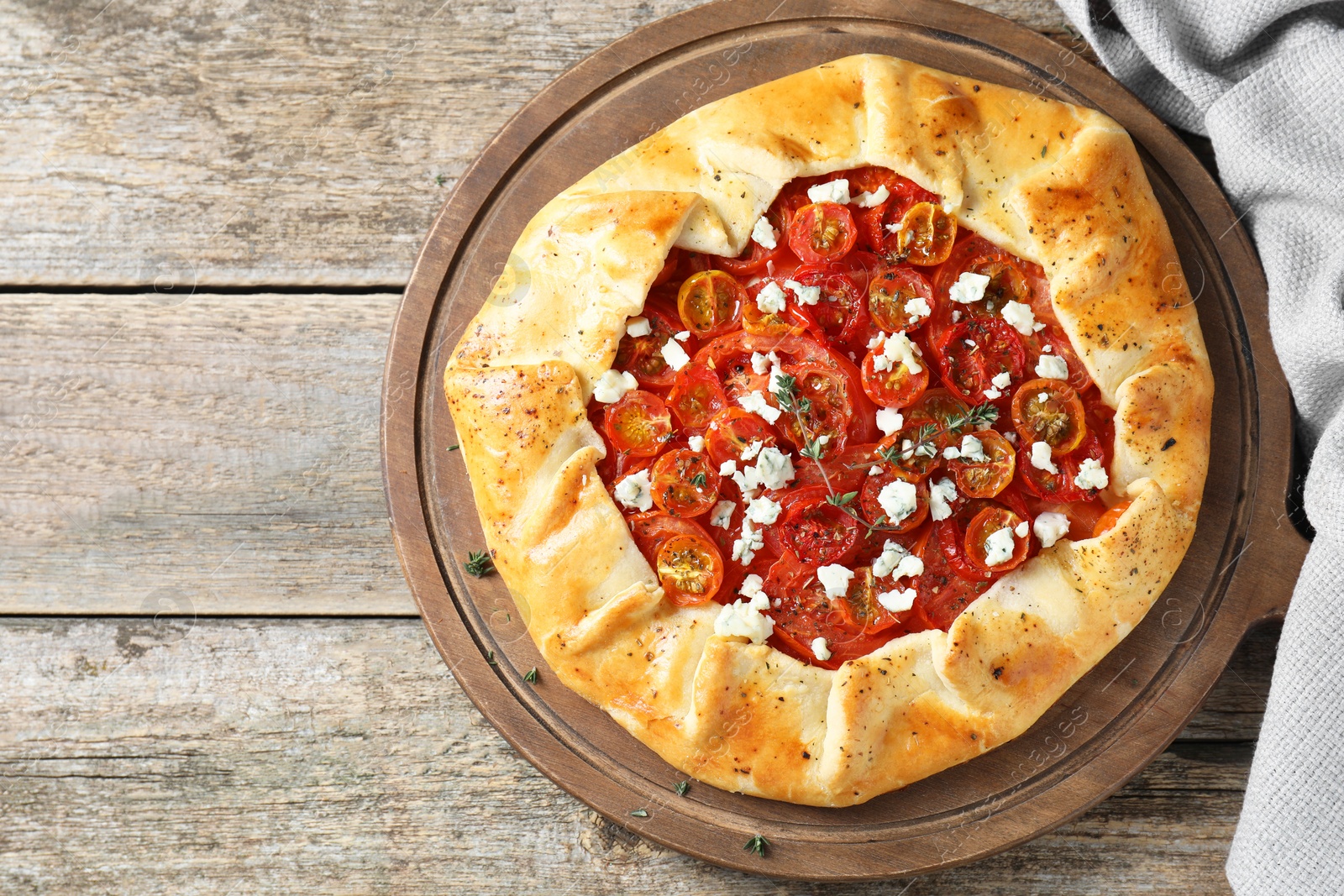 Photo of Tasty galette with tomato, thyme and cheese (Caprese galette) on wooden table, top view. Space for text