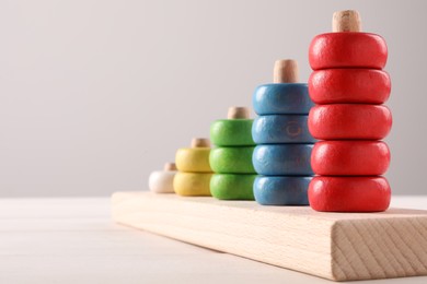 Photo of Motor skills development. Stacking and counting game pieces on white table against light grey background, closeup. Space for text