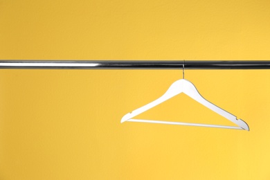 Photo of Metal rack with clothes hanger on color background, space for text